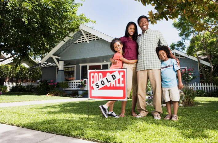 a mom, dad, young son, and younger daughter stand in front of a house with a "for sale" sign in the foreground covered by a "SOLD" sticker | Truth Tree's blog post on 8 marketing strategies schools can use to reach relocating families