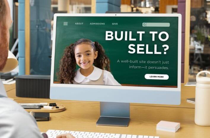 Man looking at computer screen open to a school website that reads "Built to Sell" in bold, white letters. This is a mock school homepage. This image accompanies a blog post by Truth Tree on the power of a website for school enrollment, admissions, school marketing | Truth Tree provides digital marketing strategies and solutions for private schools and independent schools